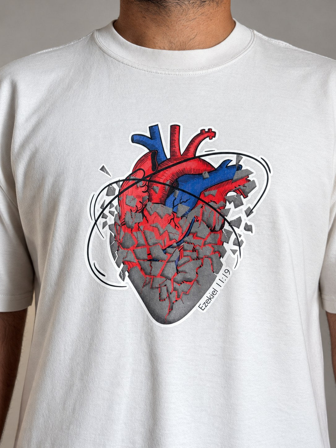 Close-up of the anatomical heart print and Ezekiel 11:19 on the Faded Bone tee